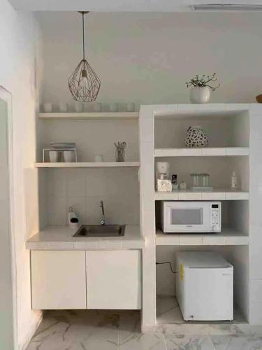 a white kitchen with a sink and a microwave at Casa Mercedes in Valladolid