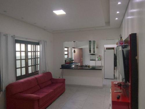 a living room with a red couch and a kitchen at Casa em Praia Grande Litoral sul in Praia Grande