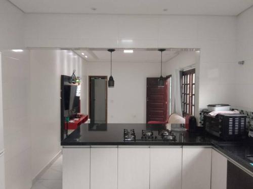 a kitchen with white cabinets and a black counter top at Casa em Praia Grande Litoral sul in Praia Grande