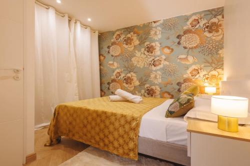 um quarto com uma cama com uma parede floral em Le Balcon du 21 em Bourg-en-Bresse