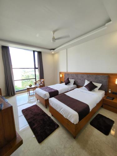 1 dormitorio con 2 camas y ventana grande en Sukoon Signature, en Indore