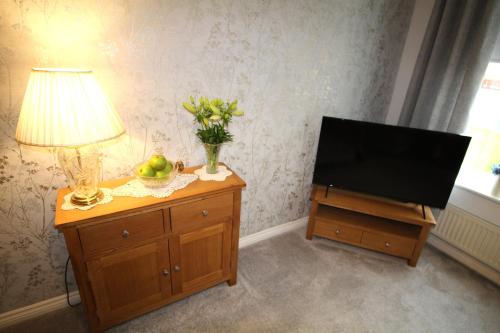 a living room with a television and a lamp on a dresser at 2 Bedroom House - Beautifully Decorated & Furnished - Parking - Large Garden in Ashington