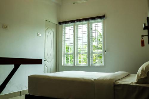 a white bedroom with a bed and a window at ADONAY INN RESIDENCY in Kalpetta