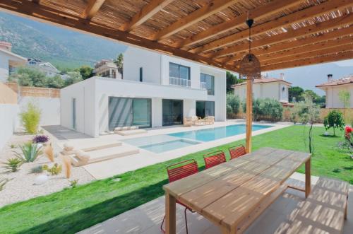 a villa with a swimming pool and a wooden table at Villa Neo with 2 private pools, bbq, jacuzzi and sauna in Fethiye