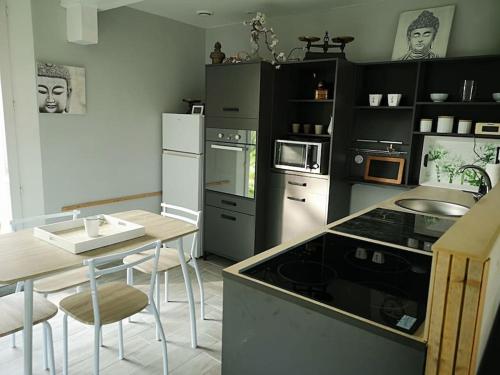 a kitchen with black and white appliances and a table at Le Petit Paradis de Noordpeene in Noordpeene