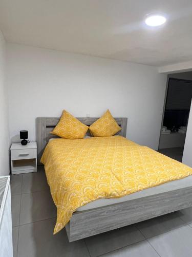 um quarto com uma cama com um edredão amarelo e almofadas em Alexa Residence - Appartement 1 em Roeselare