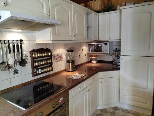 een keuken met witte kasten en marmeren aanrechtbladen bij Apartment am Teich in Öhringen