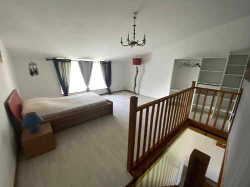1 dormitorio con 1 cama y una escalera con una lámpara de araña. en La Salamandre, en Savigné