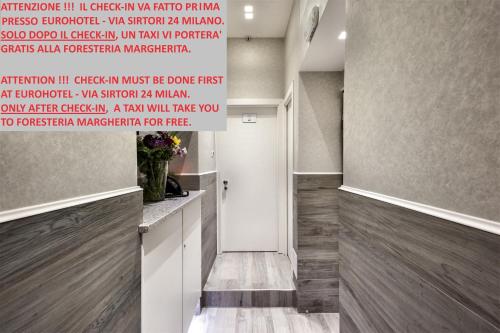 korytarz z drzwiami i ścianą z znakiem w obiekcie Guesthouse Foresteria Margherita Milano w Mediolanie