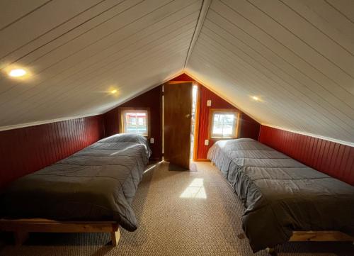 two beds in a room with red walls at Corner Hostel Puerto Natales in Puerto Natales