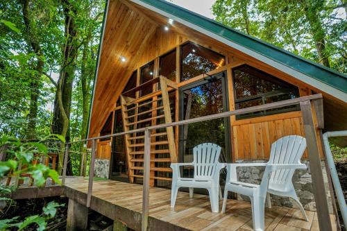 a cabin with two chairs and a table on a deck at Tityra Lodge in Monteverde Costa Rica