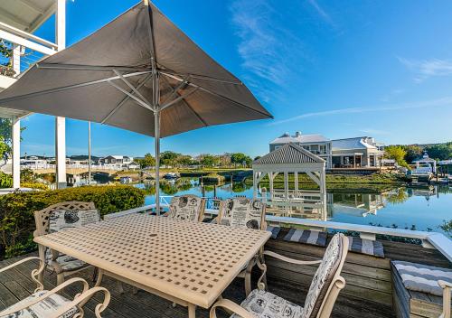 a patio with a table and chairs and an umbrella at Canal Waterside Lifestyle on Thesen Islands in Knysna
