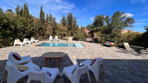 a pool with white chairs and a table and a table and a tablektop at La Molinera Rustic in Cártama