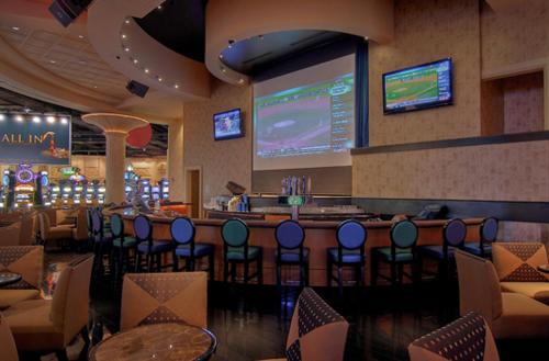 a restaurant with a bar with chairs and a large screen at Hollywood Casino Bangor in Bangor