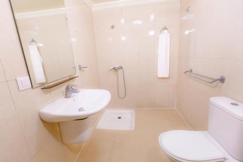 a white bathroom with a sink and a toilet at Hôtel Lynx in Agadir