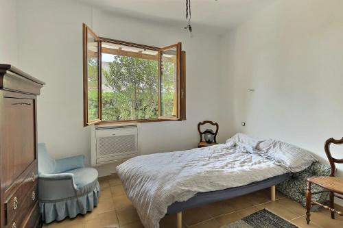 une chambre avec un lit, une fenêtre et une chaise dans l'établissement Villa au calme avec piscine et sauna, à Cazouls-lès-Béziers