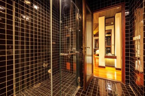 a bathroom with black tiled walls and a glass shower at Bangkok CBD Pinky Vibe Villa in Bangkok