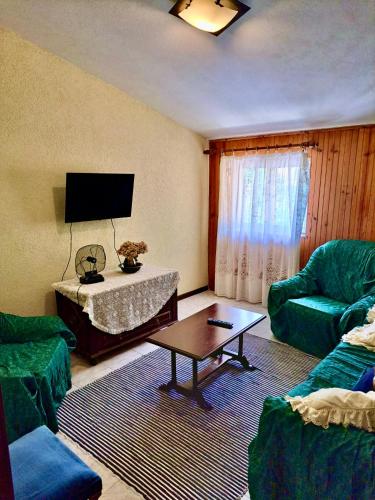a living room with two green chairs and a table at Mélita Guesthouse in Braga