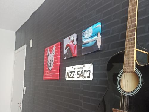 a guitar on a wall with signs on it at AP Central Park in Feira de Santana