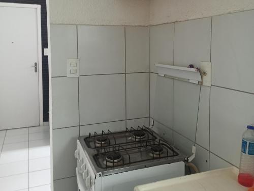 a stove top in a white tiled kitchen at AP Central Park in Feira de Santana
