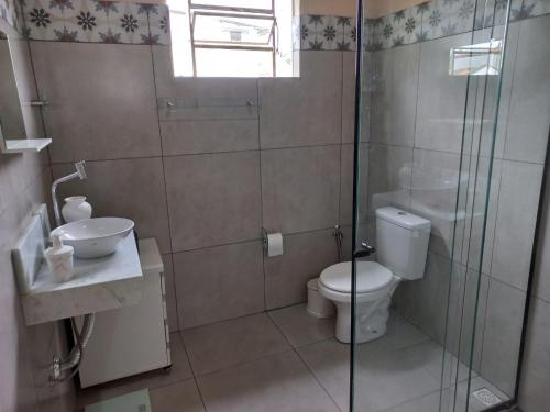 a bathroom with a toilet and a glass shower at Casinha Verde in Passa Quatro