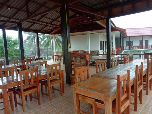 an empty restaurant with wooden tables and chairs at Sanhak Guesthouse 1 in Ban Nahin-Nai (2)