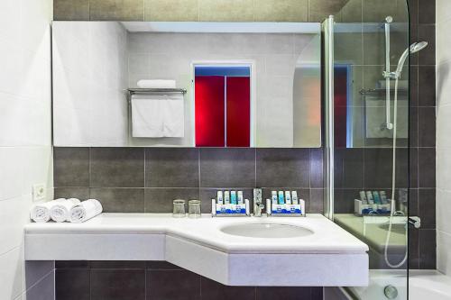 a bathroom with a sink and a glass shower at Skiathos Palace Hotel in Koukounaries