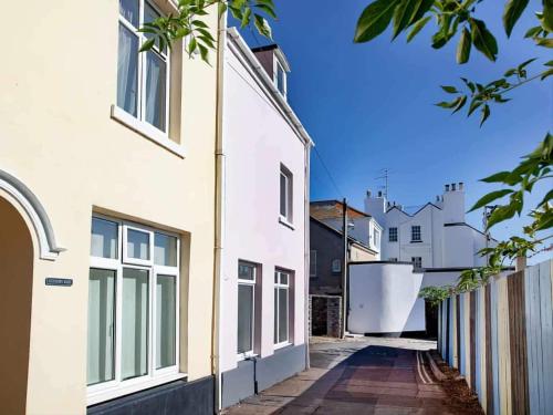 an alley between two white buildings with a fence at Customs Cottage in Teignmouth