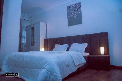 - une chambre dotée d'un grand lit avec des draps et des oreillers blancs dans l'établissement Cloud Hill, à Buea