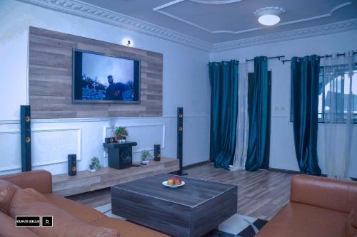 ein Wohnzimmer mit einem Sofa und einem TV an der Wand in der Unterkunft Cloud Hill in Buea