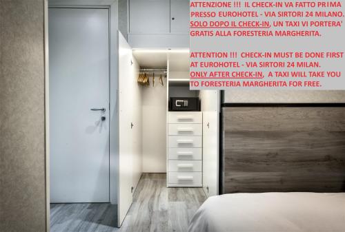ein Schlafzimmer mit einem Bett und einer Wand mit einem Schild in der Unterkunft Guesthouse Foresteria Margherita Milano in Mailand