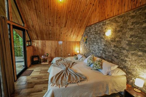 a bedroom with a bed and a stone wall at Tityra Lodge in Monteverde Costa Rica