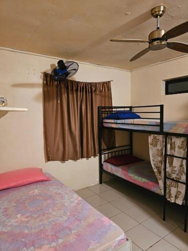 Raihei Auberge de jeunesse Chez l'habitant à Bora Bora في بورا بورا: غرفة بسريرين بطابقين ومروحة سقف