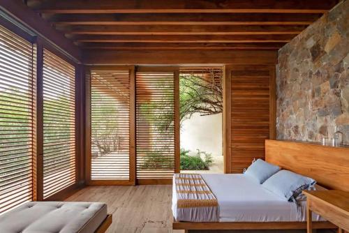 ein Schlafzimmer mit einem Bett und einer Steinwand in der Unterkunft Casa Chicatana Incredible Beach Front Villa in Zapotal