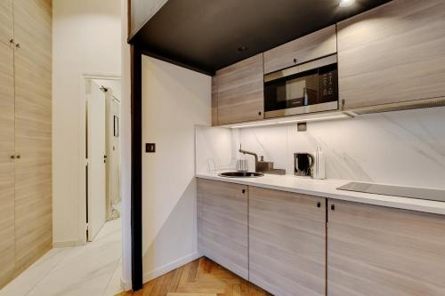 cocina con armarios de madera y microondas en Charming apartment in heart of Le Marais - GetHosted en París