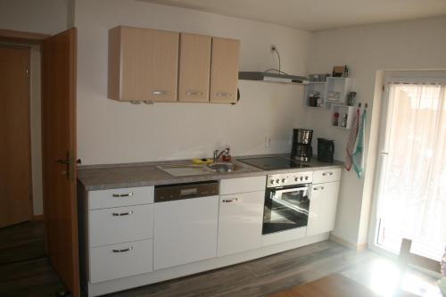 a kitchen with white cabinets and a sink and a stove at Ferienwohnung Annett in Böhlen