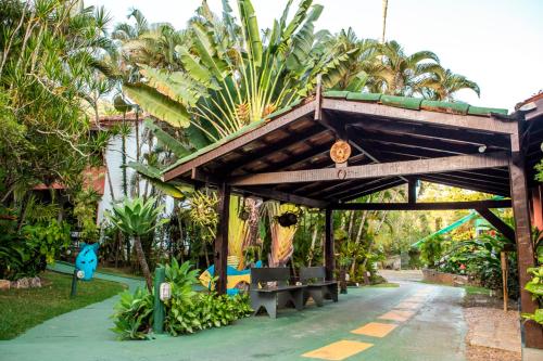 a wooden pavilion with benches and palm trees at Feiticeira Praia Hotel in Ilhabela