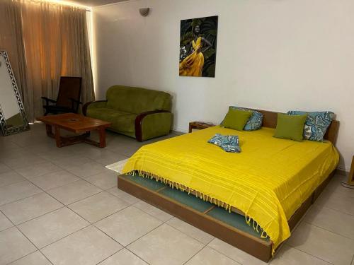 a bedroom with a yellow bed and a chair at Villa spacieuse avec piscine au Gosier - Vue sur mer in Le Gosier