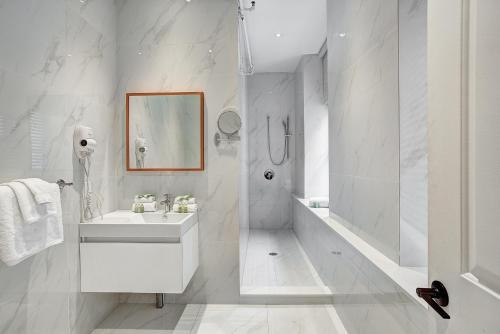 a white bathroom with a sink and a shower at Saint Sulpice Lofts by Bakan - Old Montreal in Montreal