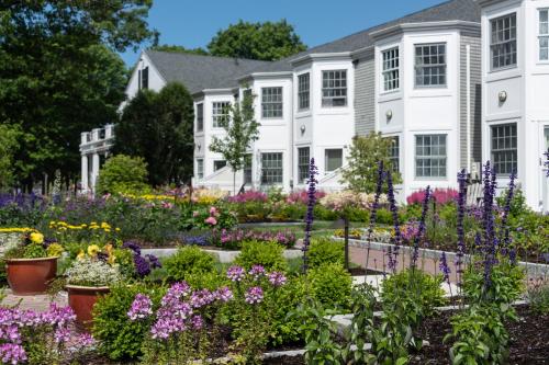 a garden in front of a house with flowers at Bar Harbor Inn and Spa in Bar Harbor