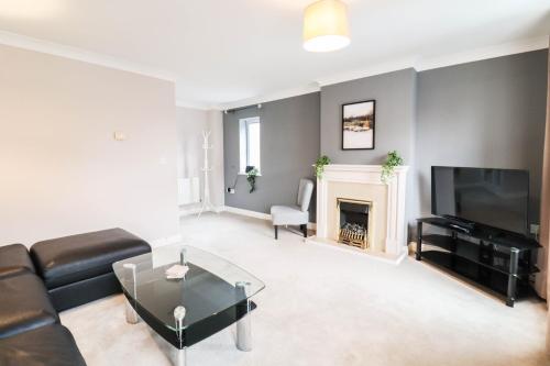 a living room with a couch and a tv and a fireplace at 4 Bedroom House with FREE WIFI AND DRIVEWAY! in Hillingdon