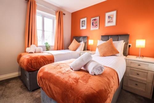 two beds in a room with orange walls at Family-Friendly 4 Bedroom House with Private Driveway in Hillingdon