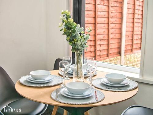 a table with plates and glasses and a vase with flowers at BIRMINGHAM HOME : STYLISH : WELCOMES ALL in Birmingham