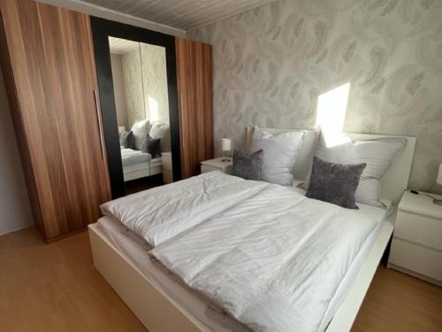 a bedroom with a large white bed with a mirror at Ferienwohnung Limper in Hilchenbach