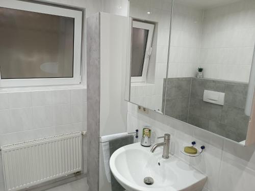 a white bathroom with a sink and a mirror at Ferienwohnung Limper in Hilchenbach