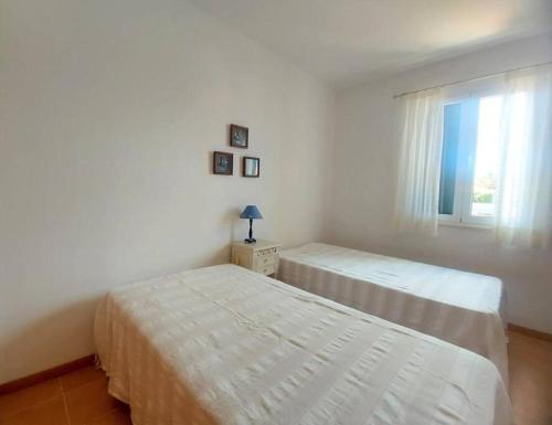 two beds in a white bedroom with a window at Desertrose in Porto Santo