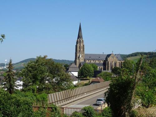 a church with a steeple and a road in front at Ferienwohnung Neli am Rhein in Rheinbrohl