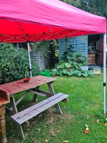 a picnic table under a red tent in a yard at The Potting Shed in Manuden