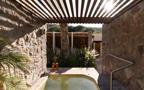 a hot tub in a courtyard with a stone wall at Armadillo Mágico in Armadillo
