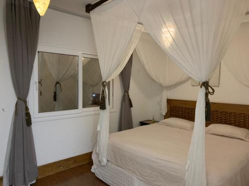 1 dormitorio con cama con dosel y cortinas blancas en Guarda do Embaú Morretes, en Guarda do Embaú